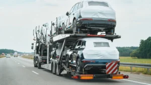Camión portavehículos de dos pisos cargado con coches circulando por una autovía